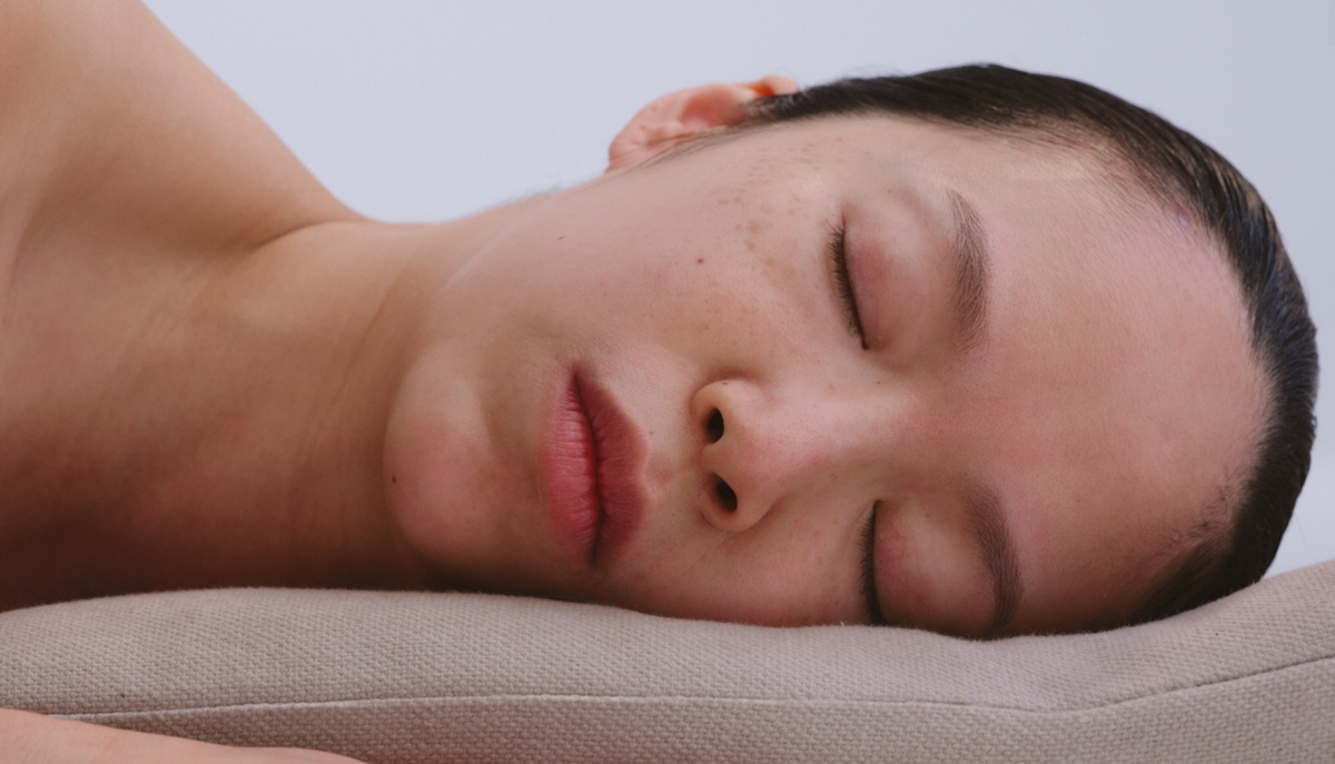 A woman sleeping, her head rested on a gray pillow