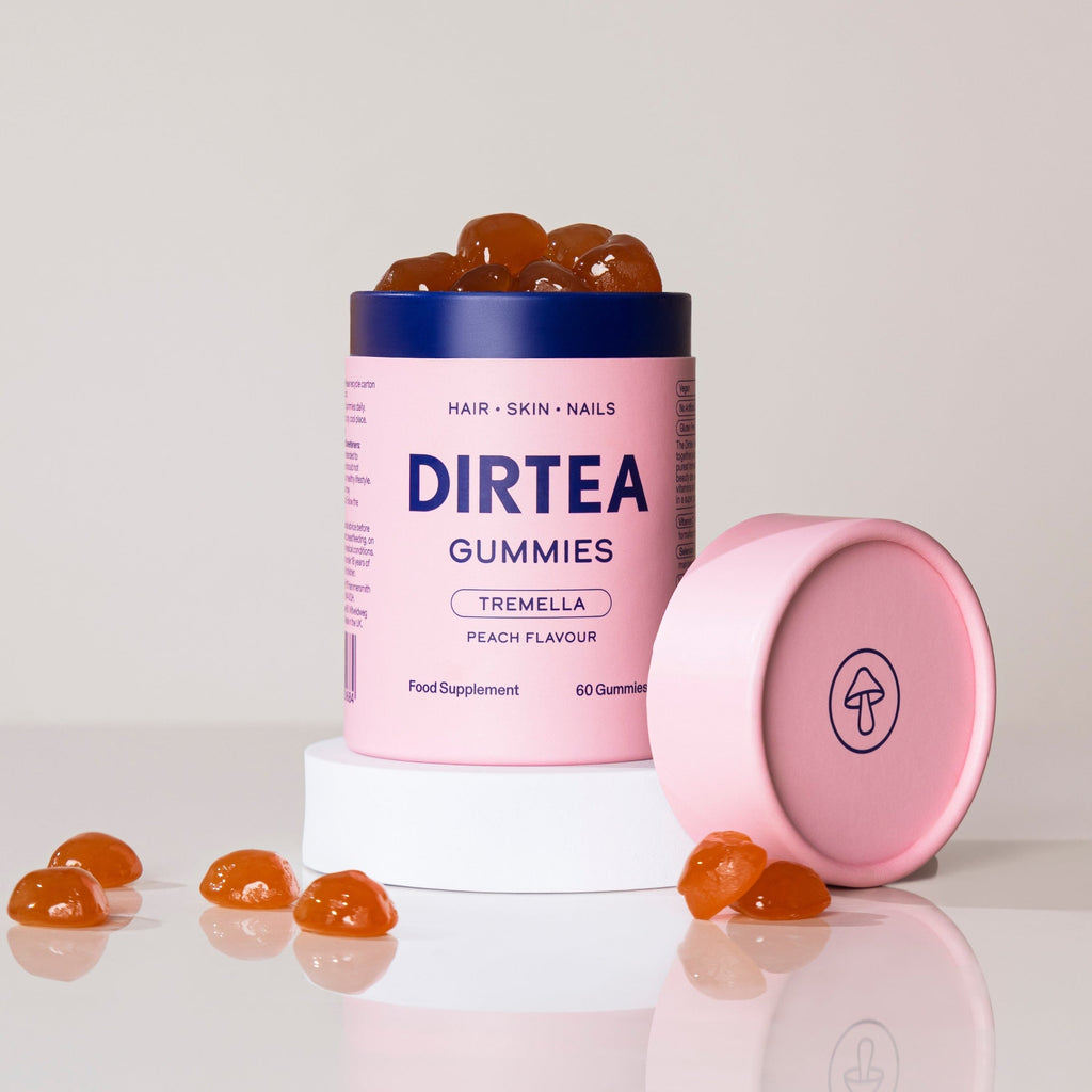 Pink container of DIRTEA Gummies with gummies on a white background